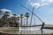 Fontaine en forme de bateau sur le Paseo Maritimo avec les palmiers et la plage en arrière plan.