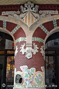 Guichet original situé à l'intérieur des colonnes en briques 
rouges ornées de céramiques encadrant l'ancienne entrée du 
Palais de la Musique Catalane. Sa construction fut commandée à Lluís 
Domènech i Montaner par l'Orfeo Catala, une association de chorale.
