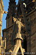 Ange sculpté dans la pierre et gargouille éclairés par le 
soleil couchant se détachant sur la façade de la cathédrale 
Sainte Eulalie de Barcelone.