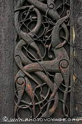 Détail des gravures sculptées dans le jambage de la porte nord de l'église en bois debout de Urnes. Elle représente la lutte du bien contre le mal, du serpent contre le lion. Ce portail de style Urnes est antérieur à la construction de l'église et a été récupéré sur l'église de 1045.