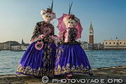 Couple de costumés posant devant le bassin de San Marco, le campanile 
et le palais des Doges lors du carnaval de Venise.